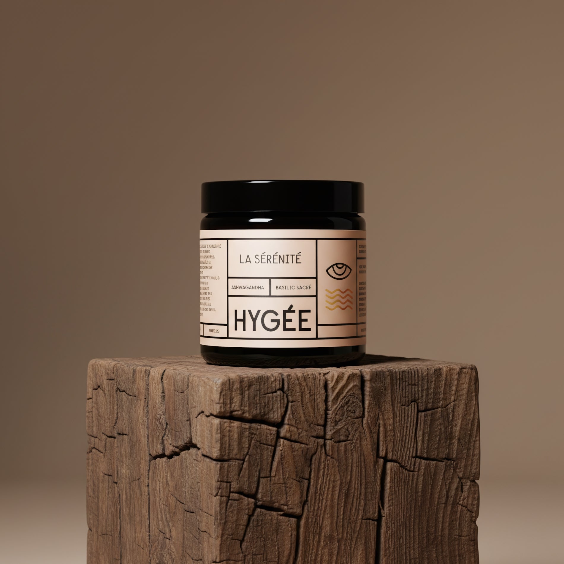 A black‑lidded amber HYGÉE La Sérénité jar sits centered on a weathered wooden plinth against a taupe background, highlighting the calm, natural texture and minimalist label design.