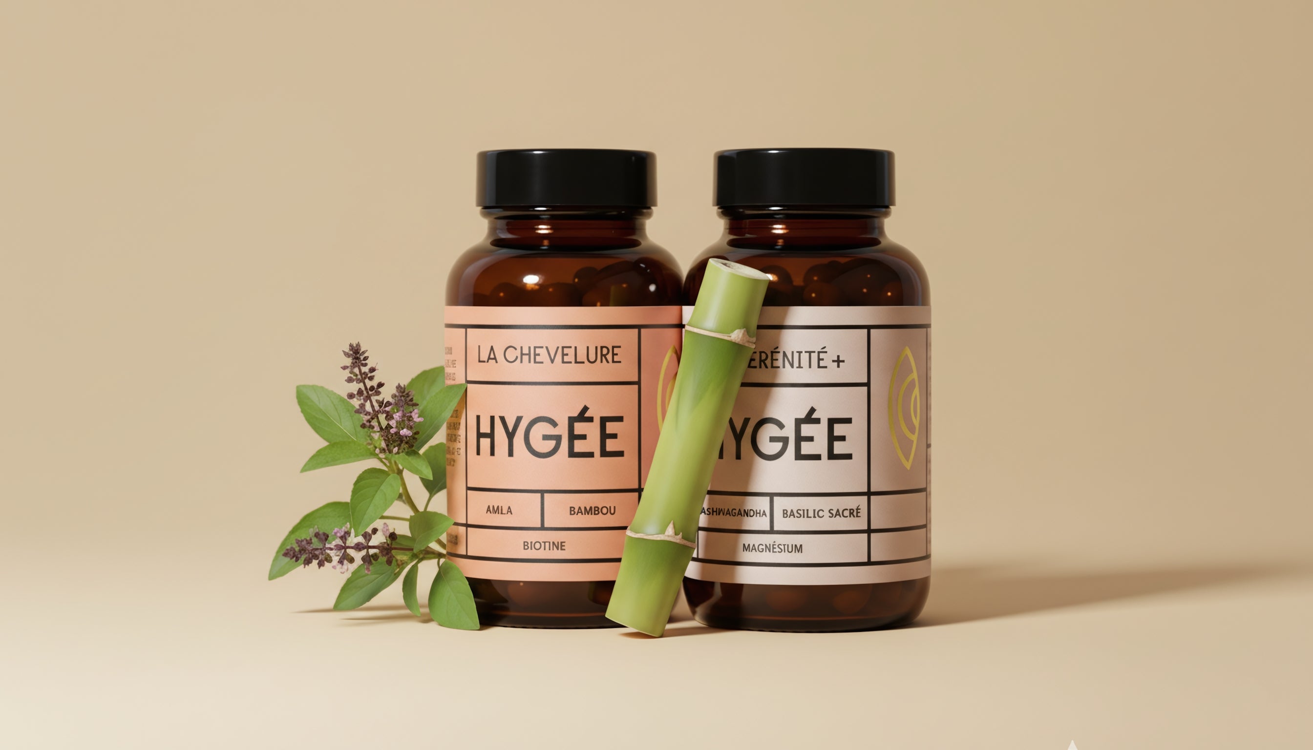 Close‑up of HYGÉE La Chevelure and La Sérénité+ amber jars on a warm beige background, framed by holy basil leaves and a pale green bamboo stalk, creating a clean, modern botanical hero image.